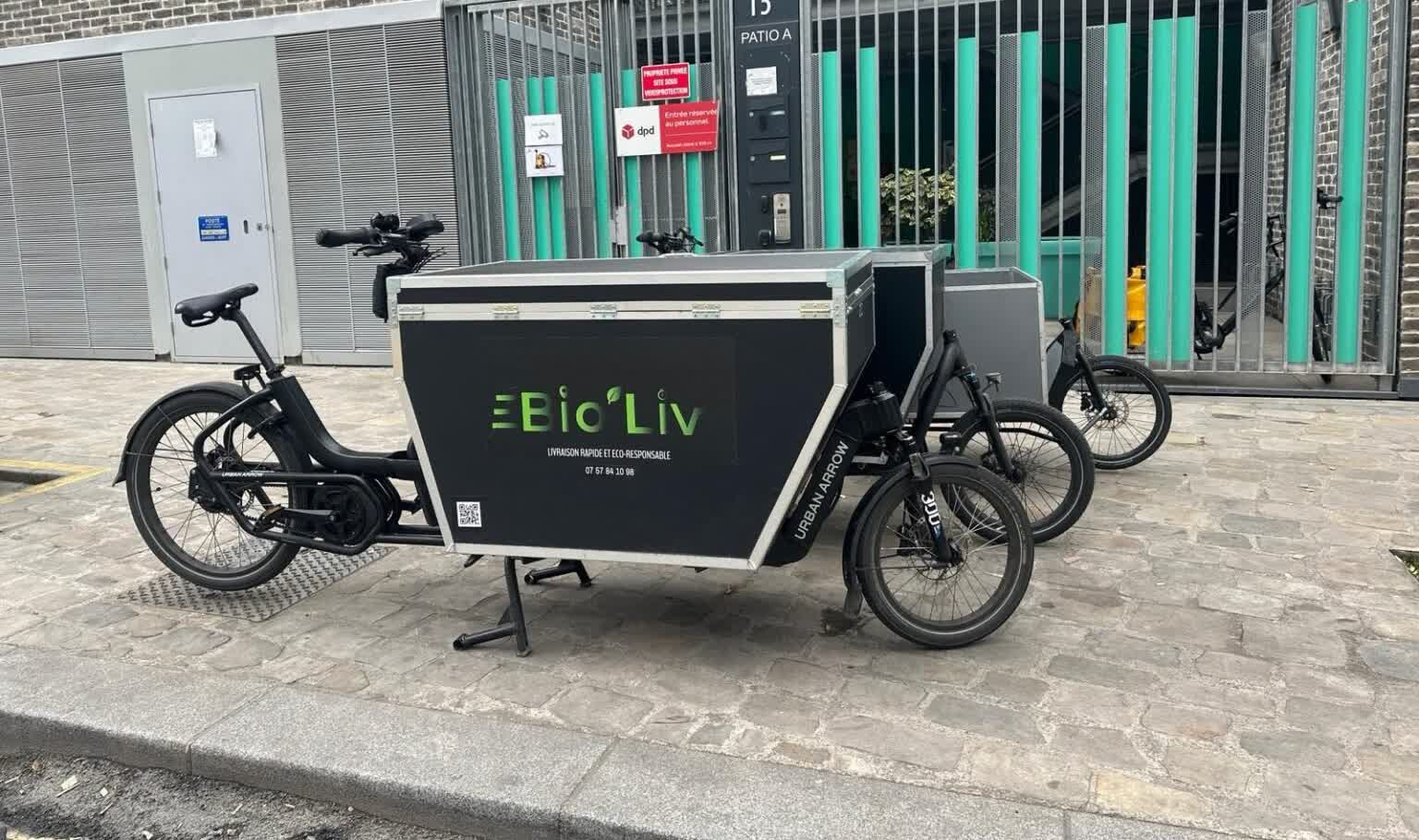 Deux vélos cargo Urban Arrow aux couleurs de Bio'Liv stationnés devant un dépôt parisien